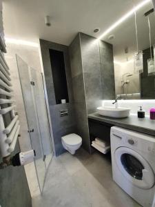 a bathroom with a toilet and a sink and a washing machine at Iława Apartamenty in Iława