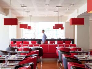 a restaurant with red chairs and a man standing in the window at Ibis Hermosillo in Hermosillo