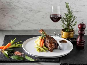 a plate with meat and vegetables and a glass of wine at Ibis Phuket Kata in Kata Beach