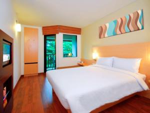 a bedroom with a large white bed and a television at Ibis Phuket Kata in Kata Beach