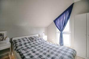 a bedroom with a bed and a window with blue curtains at Domki Kalinowa14 Kopalino in Kopalino