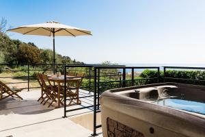 a hot tub on a balcony with a table and an umbrella at Villa du Macchione BASTIA by Location-tourisme-corse in Bastia