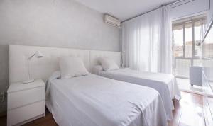 a white bedroom with two beds and a window at Apartment Montserrat 11-1 in Calafell