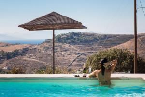 a woman in a swimming pool with an umbrella at Kea Villa Thea- Villa Ilios in Vourkari