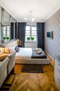 a bedroom with a bed and a desk and windows at Cracovia Apartments in Krakow