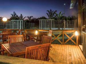 eine Holzterrasse mit Holztischen, Stühlen und Lampen in der Unterkunft Ibis Porto Alegre Assis Brasil in Porto Alegre