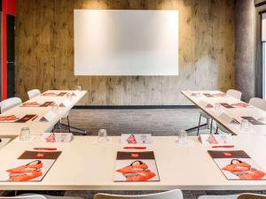 a conference room with white tables with pictures on them at ibis Montceau les Mines in Montceau-les-Mines