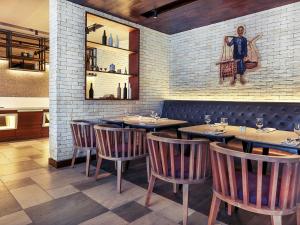 a restaurant with wooden tables and chairs and a painting on the wall at Mercure Jakarta Sabang in Jakarta