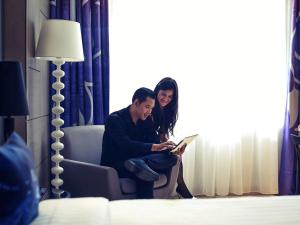 a man and woman sitting in a chair looking at a book at Mercure Jakarta Sabang in Jakarta