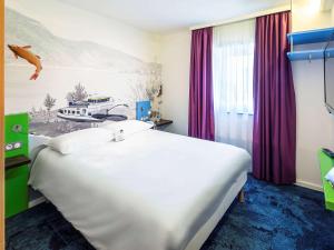 Cette chambre comprend un grand lit blanc peint. dans l'établissement ibis Styles Strasbourg Avenue du Rhin, à Strasbourg