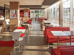 a restaurant with red chairs and tables and windows at ibis Londrina Shopping in Londrina