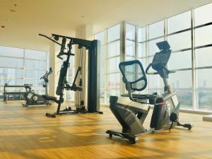 a gym with several exercise bikes in a room with windows at TreeParkCity apartments by WinsHome in Tangerang