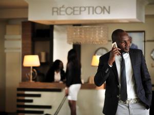 a man in a suit talking on a cell phone at Pullman Lubumbashi Grand Karavia. in Lubumbashi
