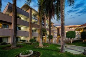 an apartment building with palm trees in front of it at La Quinta by Wyndham Pomona in Pomona