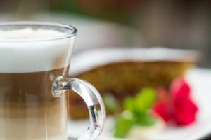 ein Glas Kaffee neben einem Teller Essen in der Unterkunft Gasthof Tschötscherhof in Kastelruth