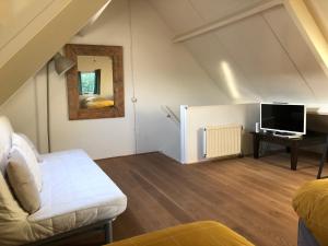 a living room with a couch and a tv in a attic at Green Garden House in Amersfoort