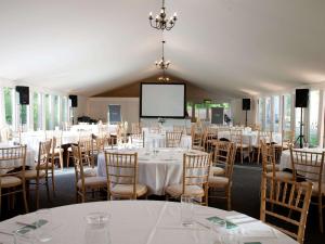 a conference room with tables and chairs and a screen at Hunton Park Hotel in Kings Langley +136 photos