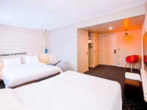 um quarto de hotel com duas camas e uma cadeira vermelha em ibis Styles Chalons en Champagne Centre em Châlons-en-Champagne