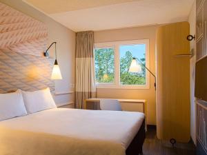 um quarto de hotel com uma cama grande e uma janela em ibis Igrejinha em Igrejinha