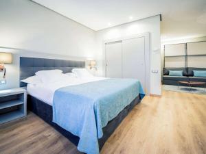 ein Hotelzimmer mit einem großen Bett und einem Stuhl in der Unterkunft Mercure Carlton Rioja in Logroño