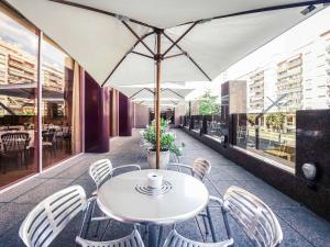 a table and chairs with an umbrella on a patio at Mercure Carlton Rioja in Logroño
