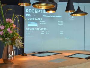 a table with a vase of flowers and lights at Ibis Brussels Erasmus in Brussels