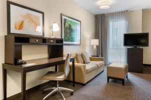 a hotel room with a desk and a couch at Staybridge Suites St. Petersburg FL by IHG in St. Petersburg