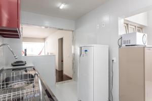 Il comprend une cuisine blanche équipée d'un réfrigérateur et d'un four micro-ondes. dans l'établissement Excelente 3 Quartos Rua Navegantes em Boa Viagem No melhor local da praia SAL802, à Récife