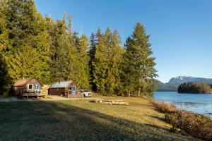 a cabin on the shore of a lake with trees at Backeddy Resort and Marina in Egmont