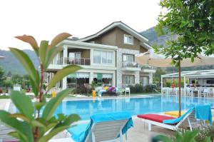 a house with a swimming pool with chairs and an umbrella at Göcek Naz Hotel in Göcek