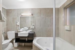 a bathroom with a tub, toilet and sink at Villa Nova Motel in Toowoomba