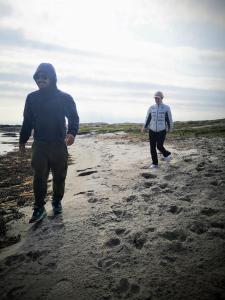 dos personas caminando por una playa de arena en Käringöns Vandrarhem en Käringön