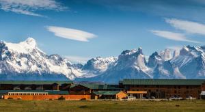 un bâtiment en face d'une montagne enneigée dans l'établissement Río Serrano Hotel + Spa, à Torres del Paine