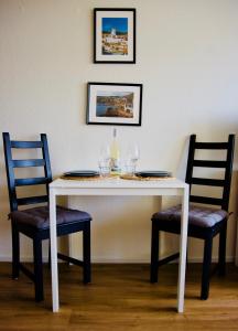 a table with two chairs and a white table with wine glasses at Gemütliches Studio für zwei in Immenstaad nur 500m vom See in Immenstaad am Bodensee