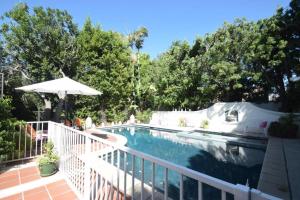 a swimming pool with a white fence and an umbrella at Beverly Hills Celebrity Home in Los Angeles
