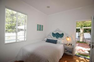 a white bedroom with a bed and a window at Beverly Hills Celebrity Home in Los Angeles