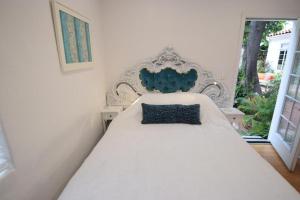 Una cama blanca con una almohada azul encima. en Beverly Hills Celebrity Home en Los Ángeles