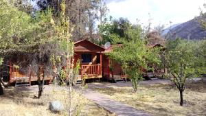 uma cabana de madeira com um alpendre e um deque em Cabañas y Hotel Rural Mirador del Maipo em San José de Maipo