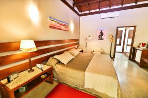 a bedroom with a bed and a table with a lamp at Bupitanga Hotel in Pipa