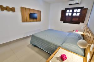 a bedroom with a bed and a tv on the wall at Pousada da Ladeira in Pipa