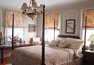 een slaapkamer met een bed, een bureau en ramen bij Port City Guest House in Wilmington