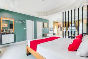 - une grande chambre avec un grand lit et des oreillers rouges dans l'établissement OYO 926 Sydney Resort, à Ban Don Pho
