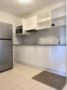 a kitchen with white cabinets and a stainless steel refrigerator at Shellharbour Resort and Conference Centre in Shellharbour