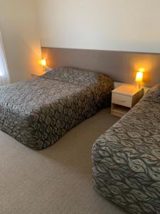 
a hotel room with two beds and two lamps at Shellharbour Resort and Conference Centre in Shellharbour
