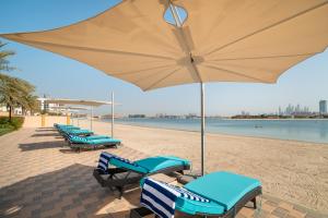 a patio area with chairs and umbrellas at GLOBALSTAY Holiday Homes - Sarai Apartments, Beach, Pool, Gym in Dubai
