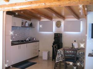 a kitchen with white cabinets and a table and a clock at B&B Suite in Viagrande