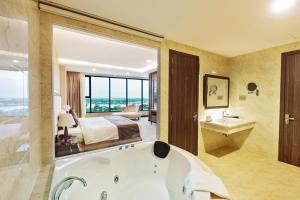 a bathroom with a tub and a bedroom with a bed at Muong Thanh Luxury Can Tho Hotel in Can Tho