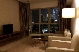 een woonkamer met een bank, een tv en een raam bij KLCC Regalia Suites Infinity Pool Kuala Lumpur in Kuala Lumpur