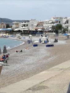 a beach with people and umbrellas and the water at Georgias Apartments in Haraki