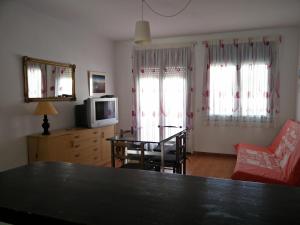 sala de estar con mesa, sillas y TV en PORT LA SARDANA EmpuriaRent en Ampuriabrava